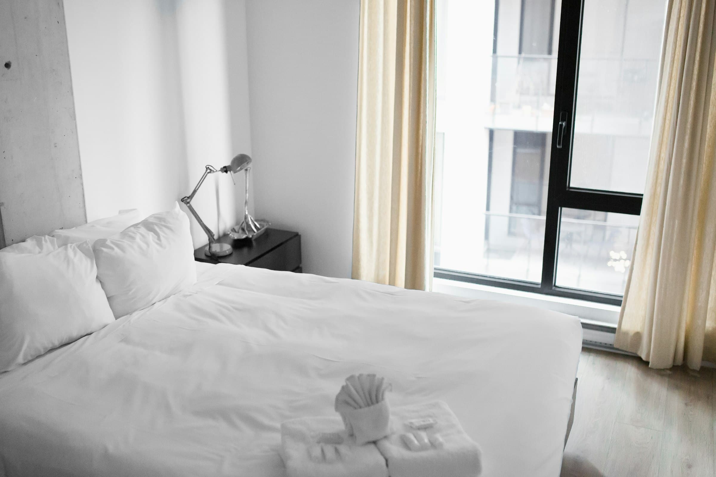 Double bed with white linen beside a large window (placeholder photo)