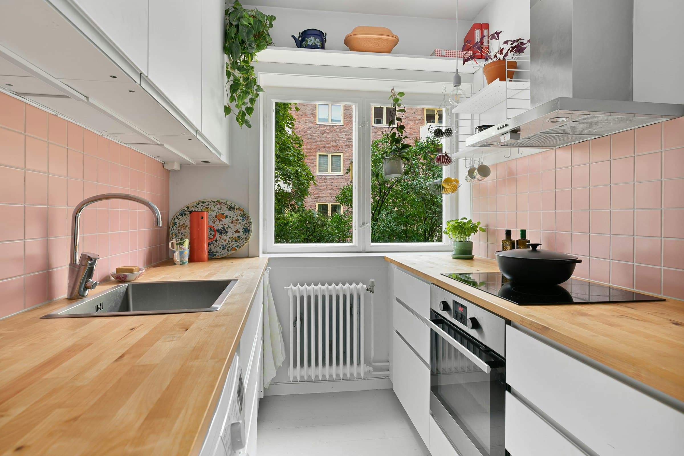 Kitchen with wooden worktops, pink tiles and a window (placeholder photo)