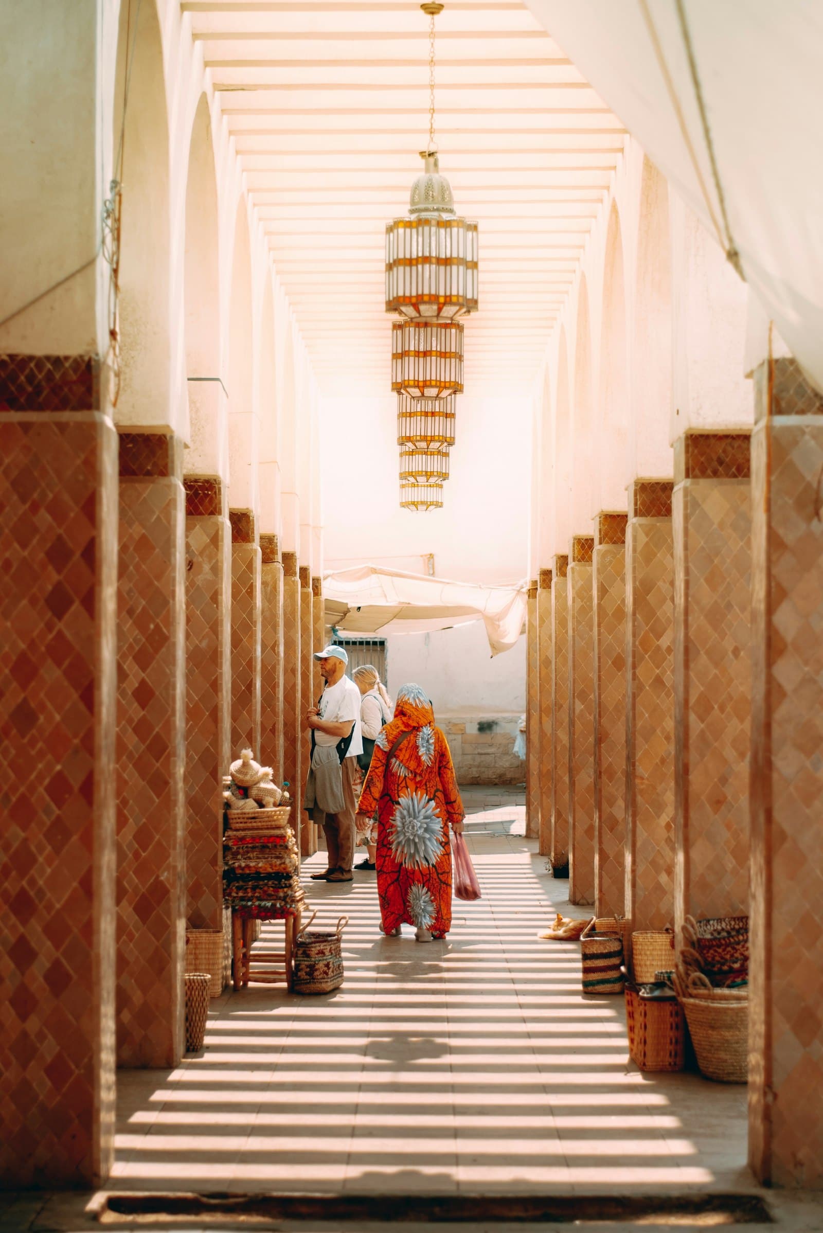 Shaded arcade of a Moroccan market with striped light on the floor
